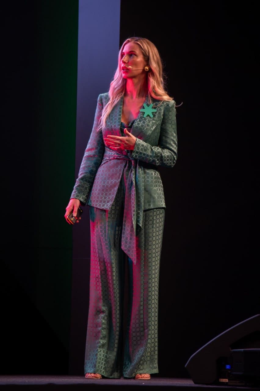 Dr. Kim Schlam onstage in green suit with headset microphone
